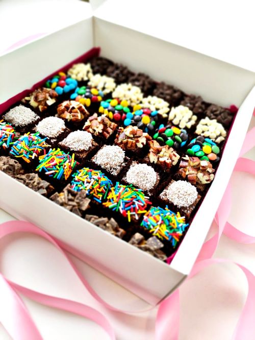 brownies amelcochados, bañados en fudge y manjar con una variedad de toppings